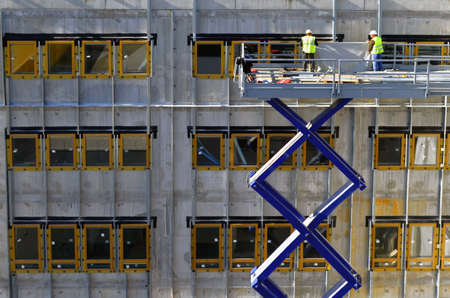 Besançon, France - March 9, 2015: Construction workmen on a cherry picker installing windows on a construction site.のeditorial素材