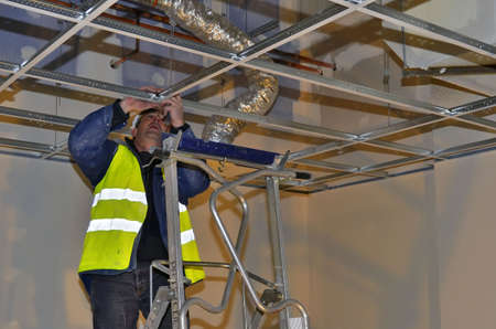 Besançon, France - February 16, 2015: Workman installing a suspended ceiling on a construction site.のeditorial素材