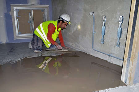 Besançon, France - January 23, 2015: Construction workman smoothing the concrete slab on a construction site.のeditorial素材