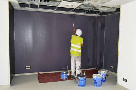 Besançon, France - June 4, 2015: Painter painting a wall in purple in a room on a construction site.のeditorial素材