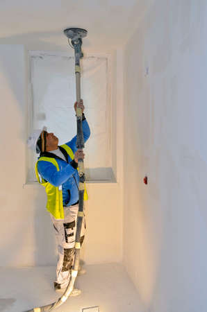 Besançon, France - February 16, 2015: Workman sanding a white ceiling on a construction site.のeditorial素材