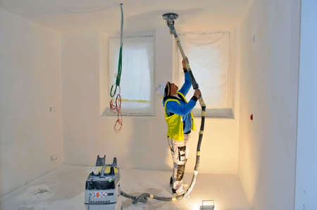 Besançon, France - February 16, 2015: Workman sanding a white ceiling on a construction site.のeditorial素材
