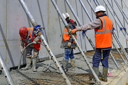 Besançon, France - May 24, 2013: Workmen pouring wet concrete on a construction site.のeditorial素材