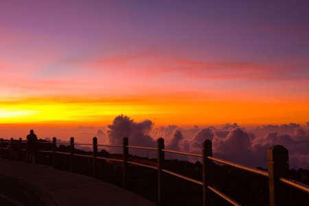 A man is witnessing the unforgettable beauty of a sunset viewed from the top of the Haleakala Vocalno, Maui, Hawaiiの写真素材