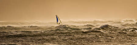 A windsurfer rides along the beautiful Maui's shores  a few minutes before sunset.の写真素材