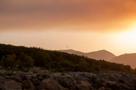 Rocks and bushes with wind turbines in background. A nearby wildfire created a thick cloud of smoke...