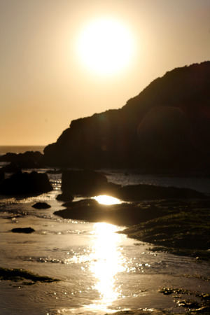 Sunset on the Pacific Ocean, northern California.  Amber glow reflects and warms the pools of salt water at the base of mountains.の写真素材