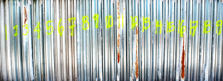 A line of Hurricane Storm Shutters in a row marked with the numbers 1 thru 19 in neon green spray...