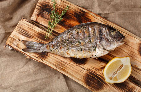 grilled fish on logs with lemon and herbs asia traditionalの写真素材