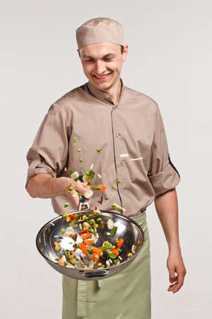 cooker chef tosses vegetables in panの写真素材