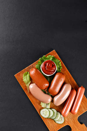 set of sausages with vegetables on cutting boardの写真素材