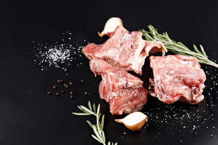 slices of frozen meat with rosemare and onion on black paperの写真素材