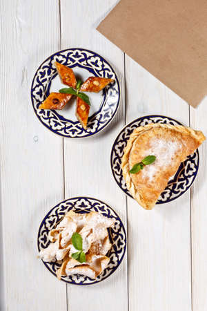 traditional asian uzbek sweets on national plates on wooden surface with tempate