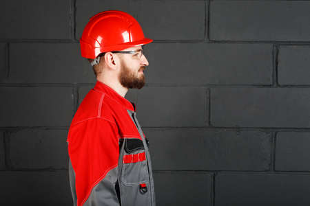 side view of worker wearing overalls and red helmet and protection eyeglassesの写真素材