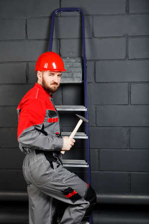 man wearing overalls with red helmet and hummer near brick wallの写真素材