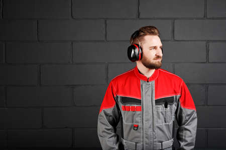 man wearing overalls with professional earplug on brick wallの写真素材