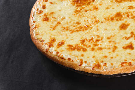Hot four cheeses delicious rustic homemade american pizza with thick crust on black tableの写真素材