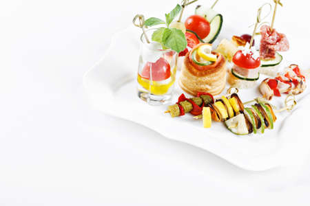 close-up view set of canapes with vegetables, salami, seafood, meat and decoration on whie plate studio isolatedの写真素材