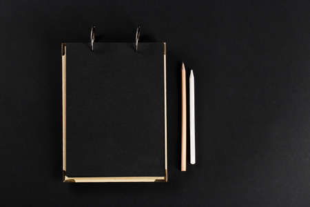 close notepad with black cover with a pencil on black backgroundの写真素材