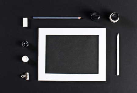 black and white mock up with white wooden photo frame with black field and set of gouache water-colors. Artist painter workplaceの写真素材