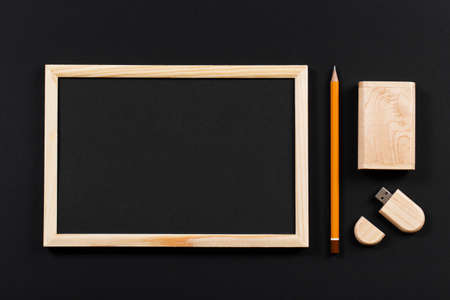 wooden frame with black field and pencil and usb flash drive in wooden box on black paper. Mockup. Real photoの写真素材