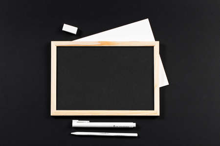 wooden frame with black field with marker and white pencil and eraser on black paper. Mockup. Real photo for you textの写真素材