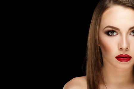 closeup portrait young beautiful brunette woman with makeup and red lips on black backgroundの写真素材