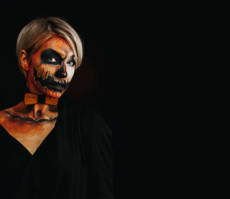 halloween portrait of body art pumpkin girl with pumpkin bowtie on black background. Real...