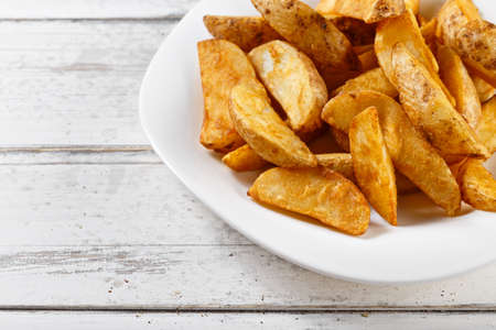 fried potatoes slices chips on wooden tableの写真素材