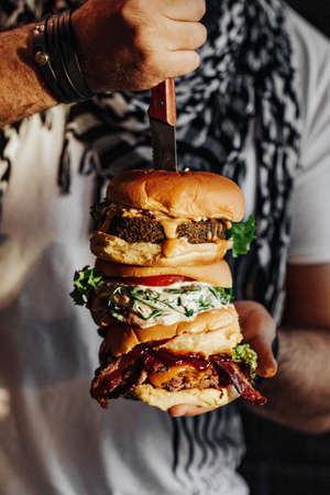 Three choices of tasty homemade burger with knife. Healthy falafel burger with fresh lettuce, savory grilled chicken with fresh cut tomato, and meaty angus beef burgerの写真素材