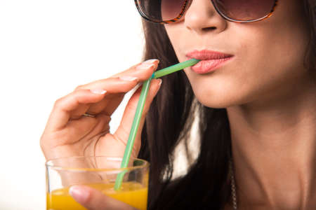 Charming girl is drinking orange juice. Pretty lady with the glass close up.の写真素材