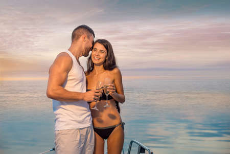 Guy with the girl relaxing on the yacht. Romantic trip. Couple drinking champagne. Loving couple relaxing on the yacht for the weekend.の写真素材