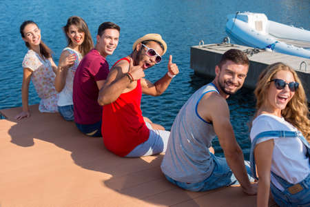 Young people is resting on the quay. Young boys and girls fun relaxing on the sea.の写真素材