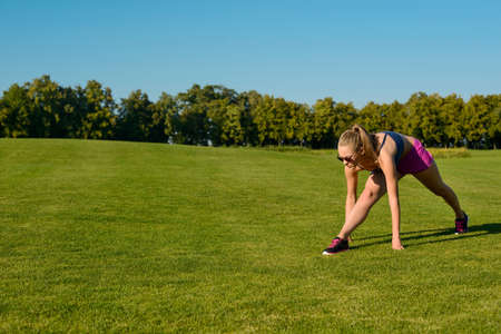 Girl go in for sport on the street. Fitness outdoors. Trainer show sports exercise on green meadow.