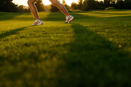 Legs of athlete. Running athlete's foot on the green grass. Running sports. Sport shoes. Fitness on the street.の写真素材