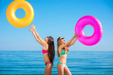 Girls at the resort. Funny girl friends sunbathe on the beach. Girls resting on the sea. Tourist ticket to the island.の写真素材