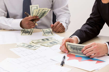 Businessmen share profit. Successful guys count money. Business success.の写真素材