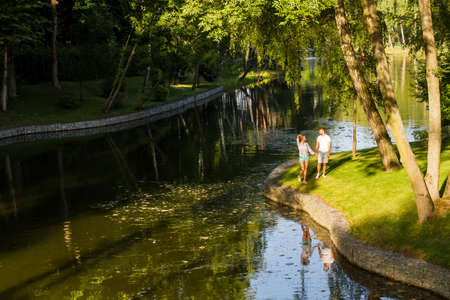 In love pair walks in the park near the lake. Beautiful romantic evening. An evening walk.の写真素材