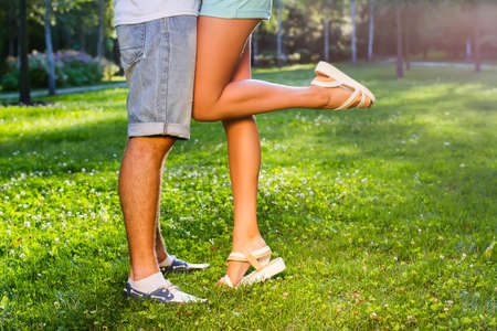 Passionate kiss. Lovers kissing in the park. Young and beautiful legs. Feet of lovers. Legs of guy and a girl.の写真素材