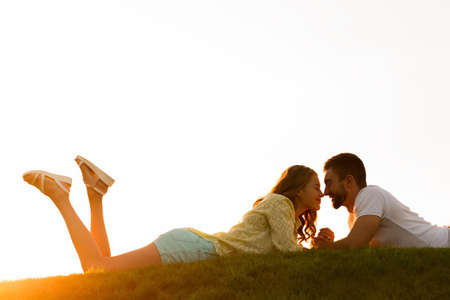 Guy and  girl enjoy each other. Lovers looking at each other. Happy man and woman. Romantic date in the rays of the evening sun.の写真素材