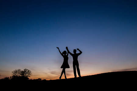Lovers admire the beautiful sky and waving their hands. Relax in nature. Camping. A couple enjoying...