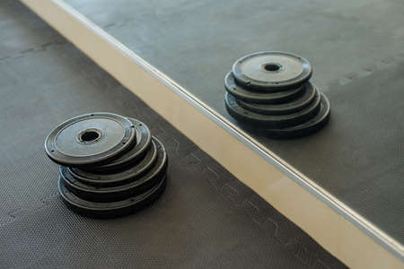 Barbells weight plate in gym. Weight plates reflected in a mirror in gym.の写真素材