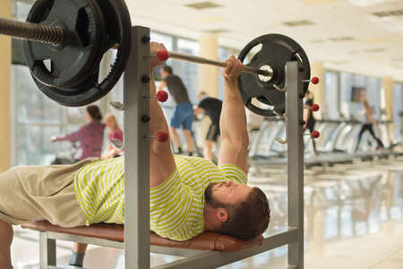 Strong man with barbell. Sportsman concentrated on the sport. Brutal man is pushing barbell.