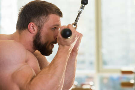 Bodybuilder in gym. Muscular man working out in gym. Sportsman doing pull-ups. Strong man is concentrated on his goal.の写真素材