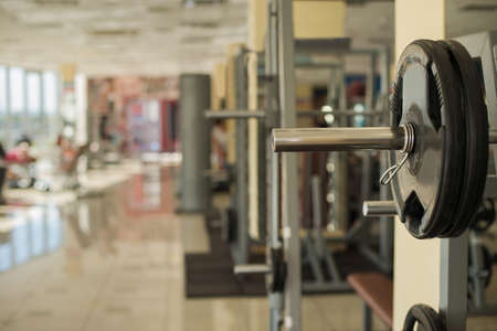 Training apparatus in gym. Barbells hanging on metal rack in gym hall. Different apparatus on the background.の写真素材