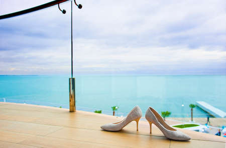 Cute bridal shoes are standing near the balcony fencing.の写真素材