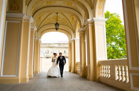 Happy newlyweds are walking under church  arches. The bride is smiling.の写真素材