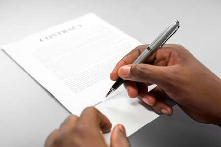 Afroamerican male signs loan contract. Just sign the paper. Beware of small font. Remember the...