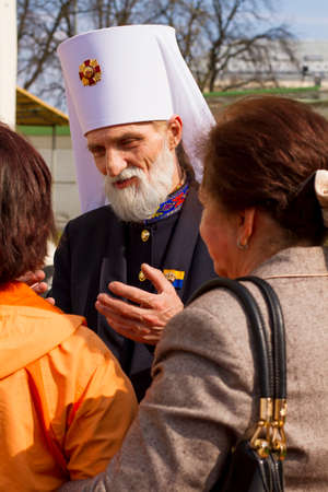 The orthodox priest is speaking to two women in christian holiday near church. They are listening to...
