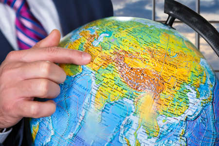 Businessman showing globe at daytime.